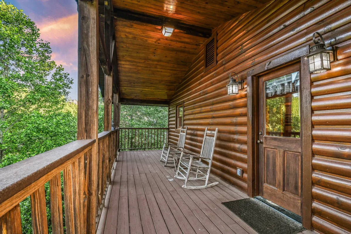 This image presents another inviting exterior view, showing rocking chairs on a porch framed by wooden railings and a doorway, suggesting a seamless transition between indoor comfort and the outdoors. The tranquil mood underlines the theme of relaxation and connection to nature.