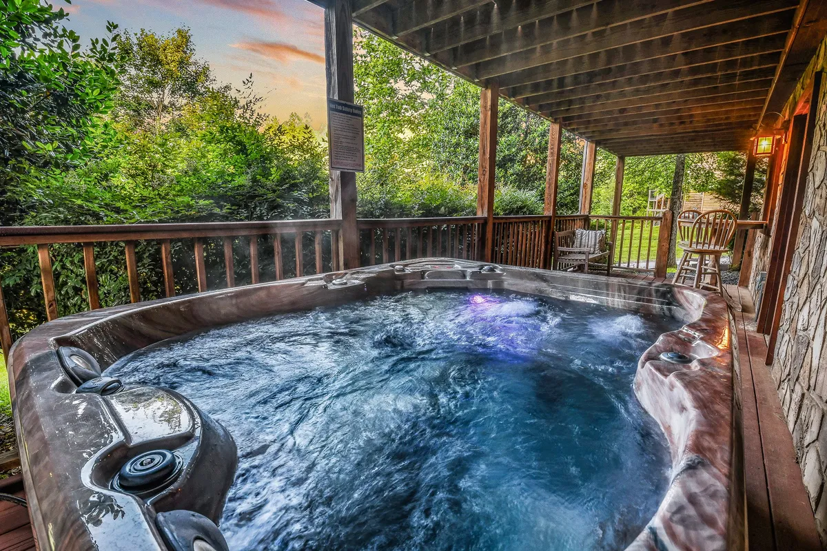This photo features a bubbling hot tub on a wooden deck, surrounded by lush greenery. The scene emphasizes tranquil outdoor relaxation and the opportunity to unwind after a day of exploring local attractions.