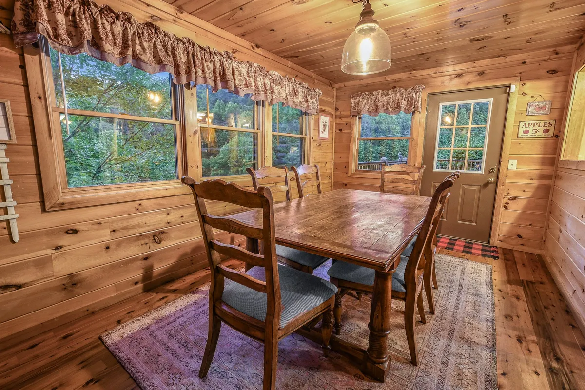 A second dining area featuring a rustic wooden table, surrounded by windows and adjacent to a door leading outside. The setup is ideal for intimate breakfasts or small group meals, with abundant natural light and a cozy, welcoming atmosphere.