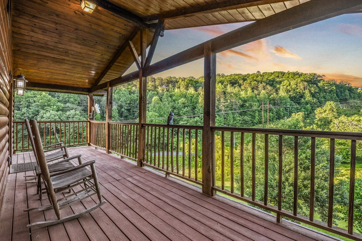 This image features a pair of classic wooden rocking chairs on a deck with a wooden railing, looking out over a serene landscape. The view invites moments of quiet contemplation, sunrise coffees, or sunset relaxation while immersed in the surrounding beauty.