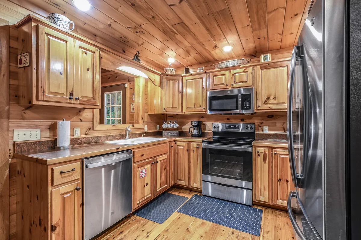 A warm and welcoming kitchen featuring wooden cabinetry, sleek stainless steel appliances, a generous kitchen island, and ample countertop space. The area is well-lit and designed for both cooking and gathering, clearly set up to accommodate family meal preparation or group entertaining.